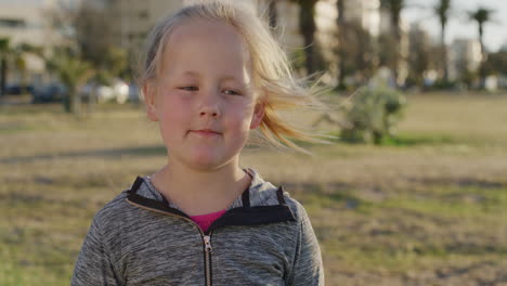 close-up-portrait-little-blonde-girl-looking-pensive-calm-child-enjoying-peaceful-summer-day-on-urban-park-windy-blowing-hair-slow-motion