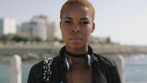 portait-of-independent-african-american-woman-on-sunny-beachfront-looking-serious-wearing-headphones