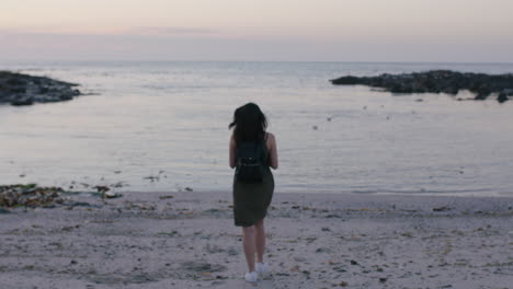 portrait-of-brunette-woman-walking-on-beach-taking-photo-of-seaside-using-phone