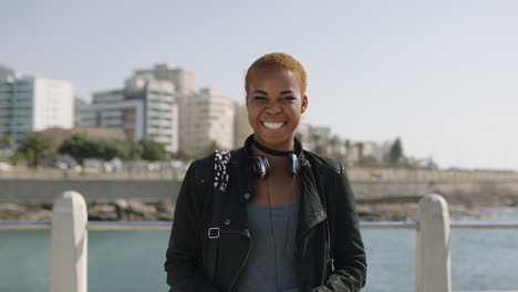 portait-of-young-african-american-woman-on-sunny-beachfront-laughing-cheerful-wearing-headphones