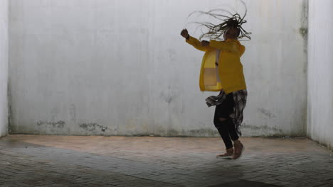 dancing-woman-young-mixed-race-street-dancer-performing-freestyle-hip-hop-moves-enjoying-modern-dance-expression-practicing-in-grungy-warehouse-wearing-yellow-jacket
