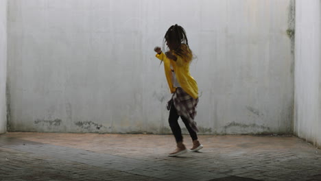dancing-woman-young-mixed-race-street-dancer-performing-freestyle-hip-hop-moves-enjoying-modern-dance-expression-practicing-in-grungy-warehouse-wearing-yellow-jacket
