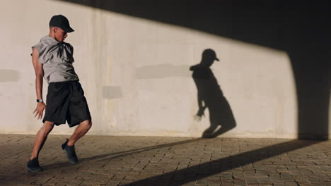 dancing-man-young-man-breakdancing-performing-backflip-freestyle-dance-moves-fit-mixed-race-male-practicing-in-city-at-sunset-with-shadow-on-wall