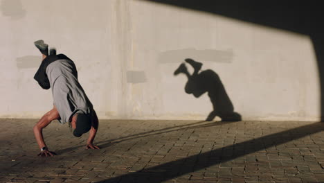 young-break-dancer-man-street-dancing-performing-various-freestyle-dance-moves-fit-mixed-race-male-practicing-in-city-at-sunset-with-shadow-on-wall
