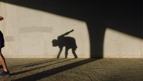 dancing-man-young-street-dancer-breakdancing-performing-various-freestyle-dance-moves-fit-mixed-race-male-practicing-in-city-at-sunset-with-shadow-on-wall