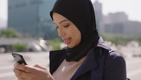 slow-motion-portrait-of-beautiful-mixed-race-muslim-woman-enjoying-using-smartphone-social-media-app-texting-in-urba-ncity-background