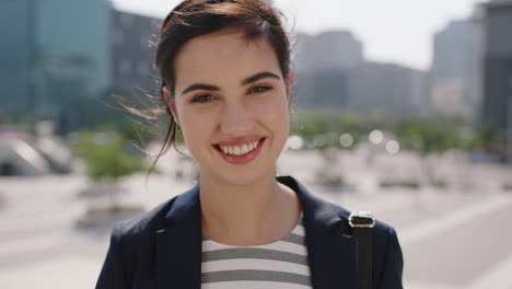 close-up-portrait-of-beautiful-middle-eastern-woman-smiling-happy-intern-listening-to-music-removes-earphones-enjoying-sunny-windy-day-in-urban-city-background