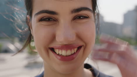 close-up-portrait-of-beautiful-middle-eastern-woman-intern-looking-at-camera-smiling-cheerful-running-hand-through-hair-in-sunny-urban-background