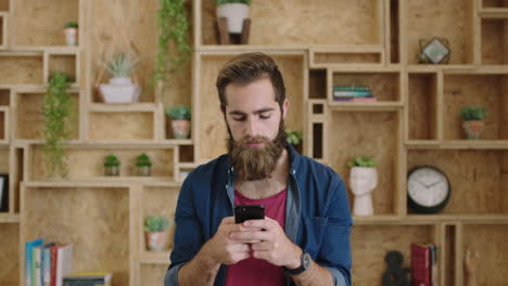 portrait-of-handsome-young-hipster-businessman-with-beautiful-beard-texting-browsing-using-smartphone-smiling-cheerful