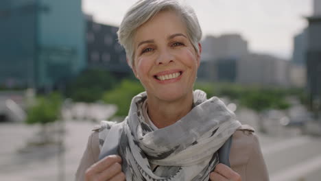 close-up-portrait-of-mature-caucasian-business-woman-looking-at-camera-smiling-cheerful-running-hand-through-hair-in-urban-city-background-wearing-scarf