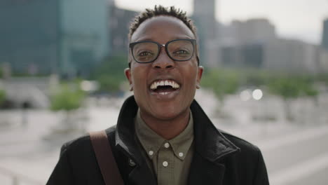Nahaufnahme-Eines-Porträts-Eines-Jungen,-Glücklichen-Afroamerikanischen-Studenten,-Der-Fröhlich-In-Die-Kamera-Lacht-Und-Eine-Brille-In-Der-Stadt-Trägt
