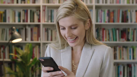 Nahaufnahme-Des-Porträts-Einer-Stilvollen-Blonden-Geschäftsfrau,-Die-Lächelt-Und-Spaß-Daran-Hat,-SMS-Zu-Schreiben-Und-Online-Mit-Der-Smartphone-Social-Media-App-Im-Anzug-Im-Bibliotheksbüro-Zu-Surfen