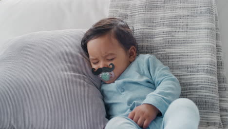 funny-baby-sleeping-with-moustache-pacifier-sucking-on-dummy-at-home-movember-concept