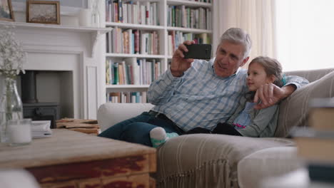 Großvater-Und-Kind-Unterhalten-Sich-Per-Video-Per-Smartphone.-Kleines-Mädchen-Teilt-Urlaubswochenende-Mit-Der-Familie.-Opa-Genießt-Es,-Zu-Hause-Mit-Seiner-Enkelin-über-Mobile-Technologie-Zu-Chatten