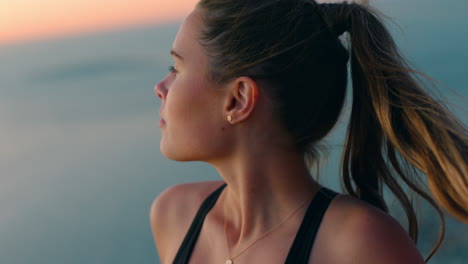 beautiful-woman-on-mountain-top-looking-at-view-of-ocean-at-sunrise-feeling-relaxed-with-wind-blowing-hair