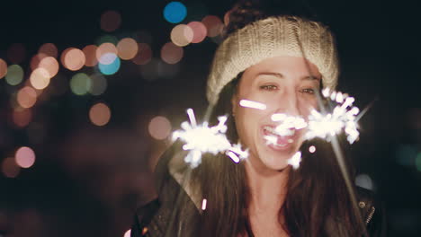 happy-caucasian-woman-holding-sparklers-dancing-on-rooftop-at-night-celebrating-new-years-eve-enjoying-holiday-celebration