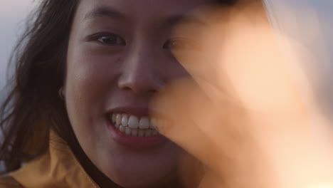 close-up-portrait-of-happy-asian-woman-holding-sparklers-celebrating-new-years-eve-smiling-enjoying-independence-day-celebration-on-beach-at-sunset