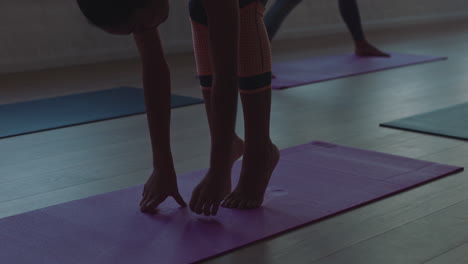 yoga-class-young-mixed-race-woman-stretching-body-on-exercise-mat-preparing-for-ealy-morning-workout-getting-ready-in-fitness-studio-at-sunrise