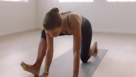 Full length view of flexible young woman with slim fit body working out in  fitness center hall, doing yoga, exercising with mat on wooden floor, doing  downward facing dog or adho mukha
