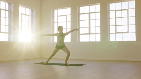 healthy-yoga-woman-practicing-warrior-pose-enjoying-fitness-lifestyle-exercising-in-workout-studio-stretching-training-on-exercise-mat-at-sunrise