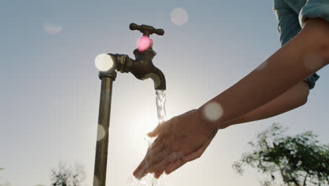 farmer-woman-washing-hands-under-tap-on-rural-farm-freshwater-flowing-from-faucet-with-afternoon-sun-flare