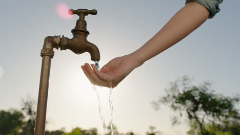 farmer-woman-washing-hand-under-tap-on-rural-farm-freshwater-flowing-from-faucet-with-afternoon-sun-flare