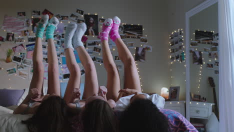 happy-teen-girls-lying-on-bed-at-home-with-legs-up-having-fun-wiggling-feet-hanging-out-wearing-pajamas-enjoying-relaxing-morning-on-weekend