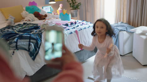 happy-little-girl-playing-dress-up-in-bedroom-jumping-excited-with-mother-taking-photo-using-smartphone-sharing-on-social-media