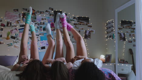 happy-teen-girls-lying-on-bed-at-home-with-legs-up-having-fun-wiggling-feet-hanging-out-wearing-pajamas-enjoying-relaxing-morning-on-weekend