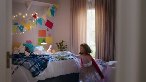 Fröhliches-Kleines-Mädchen,-Das-In-Kostümen-Auf-Dem-Bett-Springt-Und-Ein-Spiel-Spielt,-Genießt-Spielerische-Fantasie-Im-Farbenfrohen-Schlafzimmer-Zu-Hause