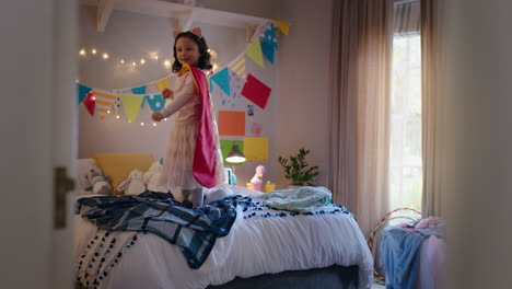happy-little-girl-jumping-on-bed-wearing-costume-playing-game-enjoying-playful-imagination-in-colorful-bedroom-at-home
