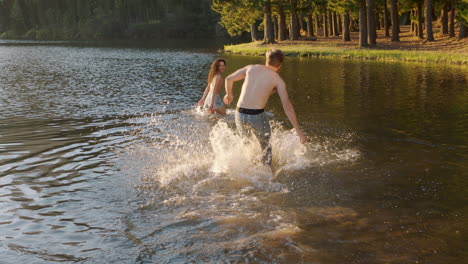 happy-couple-splashing-in-lake-at-sunset-young-man-picks-up-girlfriend-splash-in-water-having-fun-game-enjoying-romantic-summer-love