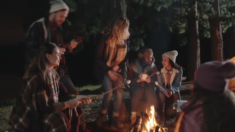happy-friends-camping-sitting-by-campfire-in-forest-at-night-chatting-drinking-hot-chocolate-roasting-marshmallows-sharing-warmth-enjoying-outdoor-adventure