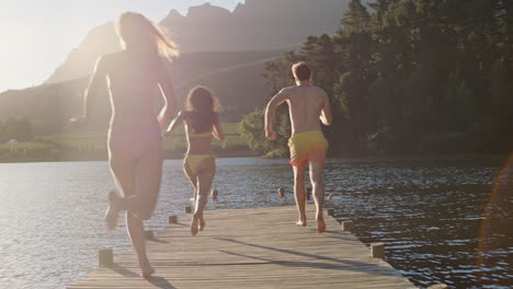 happy-friends-running-jumping-off-jetty-in-lake-at-sunset-having-fun-splashing-in-water-enjoying-freedom-sharing-summertime-adventure