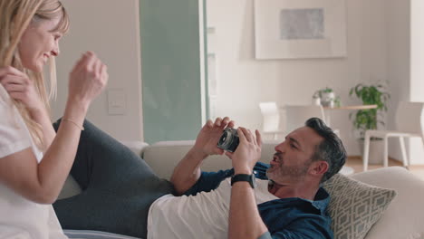 happy-couple-taking-photo-together-using-camera-having-fun-at-home-on-sofa-playfully-enjoying-romantic-relationship