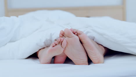 Couple,-feet-and-together-in-bed-on-holiday