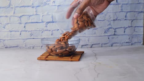 Putting-almond-nuts-in-a-bowl-on-table