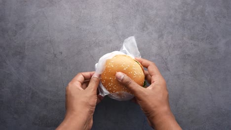 Men-removing-a-paper-packet-from-a-beef-burger,