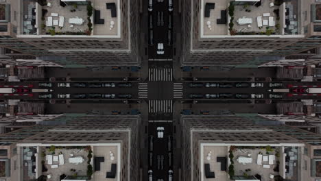 Birds-eyes-shot-of-vehicles-passing-symmetrical-crossroad-among-tall-buildings-in-city.-Abstract-computer-effect-digital-composed-footage
