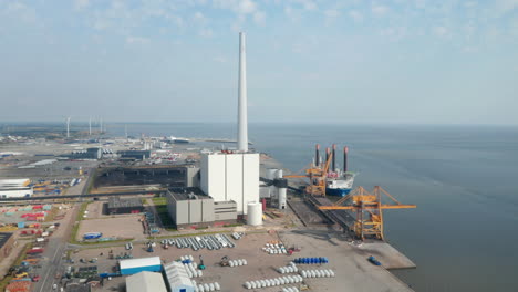 Aerial-view-over-the-city-of-Esbjerg-with-slow-rotation-on-harbor-and-tallest-chimney-of-Scandinavia-of-the-coal-and-oil-fueled-power-plant