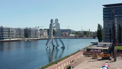 Forwards-fly-to-Molecule-Man,-30-meters-height-sculpture-on-Spree-River.-Three-human-silhouettes-leaning-toward-each-other.-Berlin,-Germany