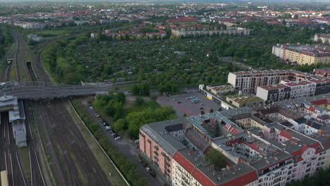 Forwards-fly-above-multi-track-railway-line-at-Bosebrucke.-Tilt-up-reveal-of-buildings-in-urban-neighbourhood.-Berlin,-Germany