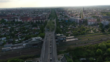 Late-afternoon-aerial-orbit-shot-around-Bosebrucke-bridge-spanning-over-multi-track-railway-line.-Panoramic-view-of-large-city.-Berlin,-Germany