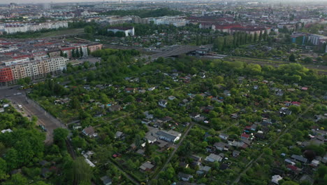 Tilt-and-pan-footage-of-greenery-in-large-city.-Island-of-trees-and-vegetation-among-blocks-of-residential-buildings.-Revealing-cityscape-with-Fernsehturm.-Berlin,-Germany