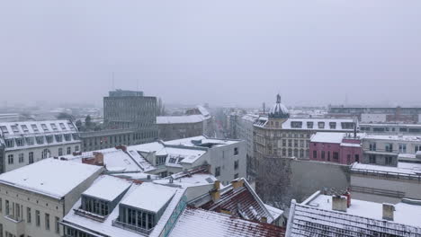 Forwards-fly-above-buildings-in-urban-neighbourhood-in-winter.-Snowing-in-city.-Revealing-street-and-apartment-houses.-Berlin,-Germany