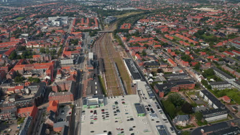 Backwards-fly-above-train-station-located-in-centre-of-small-Danish-town.-Aerial-panoramic-view-of-small-Danish-town.-Esbjerg-Banegård,-Esbjerg,-Denmark.