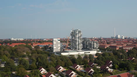 Bird's-eye-drone-view-of-the-construction-of-Esbjerg-Tower,-future-students-home-and-hotel-apartments.-Aerial-view-revealing-the-chimney-of-the-power-station
