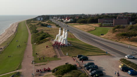 Aerial-view-of-Esbjerg-seaside,-with-slow-camera-rotation-around-Man-Meets-the-Sea-sculpture.-High-Angle-view-of-the--famous-sculpture-od--with-lots-of-turists-visiting.-Esbjerg,-Denmark