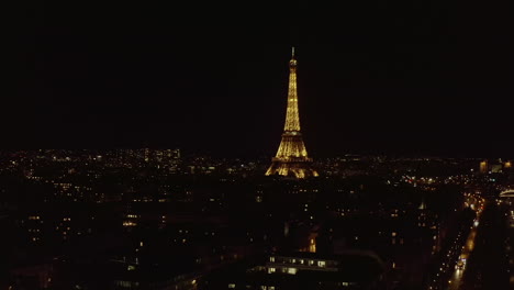 Statische-Luftaufnahme-Des-Beleuchteten-Eiffelturms-über-Dem-Nächtlichen-Stadtzentrum.-Hohe-Stahlkonstruktion-Mit-Aussichtsplattformen.-Paris,-Frankreich