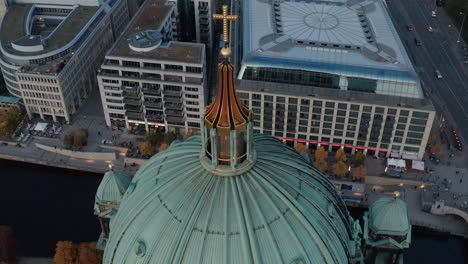 Tilt-down-footage-of-Berlin-Cathedral-dome-roof-with-religious-cross.-Commercial-buildings,-DDR-museum-and-traffic-in-surrounding-street-in-background.-Berlin,-Germany.